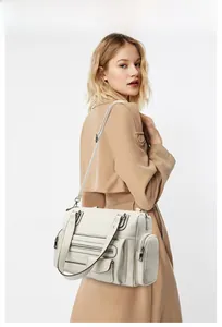 Detail view of cream multi-pocket leather handbag with functional zippers and pockets