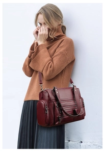 Close-up of a burgundy multi-pocket leather handbag on a model for casual winter outfit