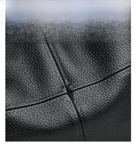 Close-up of black litchi grain leather texture and durable cross stitching detail