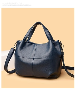 Close-up of deep blue pebbled leather tote with crossbody strap and cross-stitch detail
