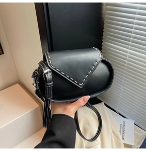 Detail of black crossbody bag with white contrast stitching and silver metal hardware