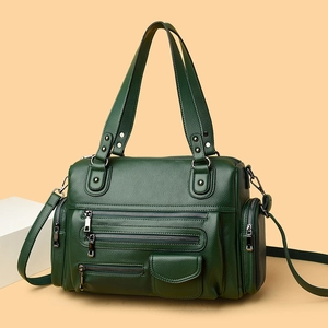 Detail of dark green pebbled leather bag featuring multiple functional zippers and silver hardware