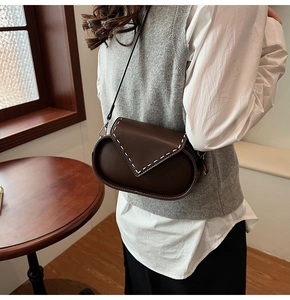Detail of vintage dark brown leather crossbody bag with white contrast stitching accents