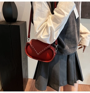 Close-up of a vintage red shoulder bag with white contrast stitching on model