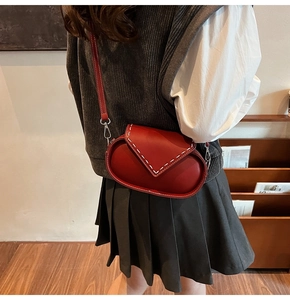 Detail of red matte leather crossbody bag with white stitching shown on a model