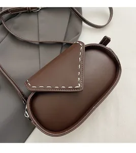 Close-up of vintage brown oval crossbody bag featuring white contrast stitching details