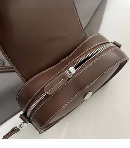 Detail of smooth silver zipper and white contrast stitching on vintage brown leather bag