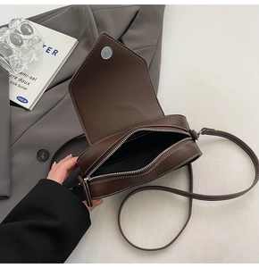 Detailed shot of a brown crossbody bag with contrast stitching and magnetic buckle closure