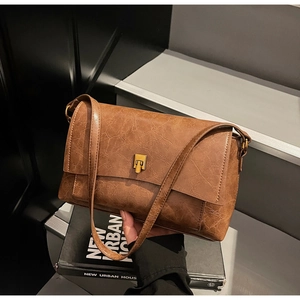 Détail du sac en cuir marron vintage avec serrure dorée et texture craquelée