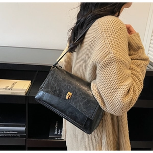 Détail du sac bandoulière vintage en cuir noir texturé avec boucle carrée en métal doré