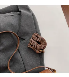 Détail d'une bandoulière en cuir marron réglable avec boucle dorée pour sacs vintage