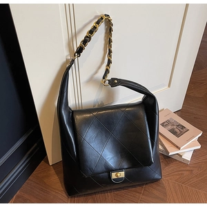 Detail of black quilted leather shoulder bag with gold chain strap and metal lock