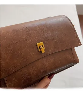 Détail d'un sac à main en cuir marron vintage avec un fermoir métallique doré rectangulaire