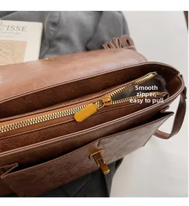 Gros plan sur la fermeture éclair dorée et la texture en cuir marron vintage du sac