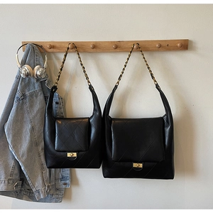 Detail of black quilted leather shoulder bags with gold chain straps in two sizes