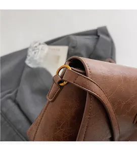 Détail du crochet en métal doré durable sur un sac à bandoulière en cuir PU marron vintage