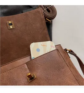 Détail du sac en cuir marron vintage montrant la poche avant et le fermoir aimanté