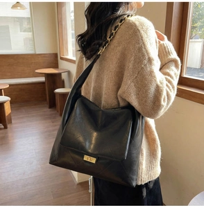 Detail of a large black quilted leather shoulder bag with gold chain and twist lock