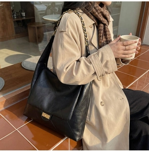 Detailed view of black quilted shoulder bag featuring gold twist lock and woven chain strap