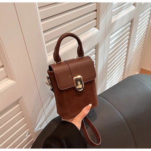 Close-up of retro brown leather crossbody bag with vintage gold lock and round handle