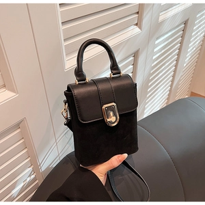 Detail of black suede and smooth leather bag featuring a gold shield-shaped lock clasp