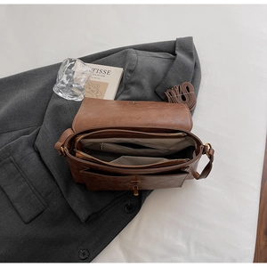 Détail du sac en cuir marron avec compartiments internes et bandoulière ajustable