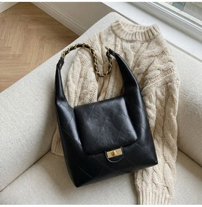 Detailed view of black quilted leather shoulder bag with gold chain and metal twist lock