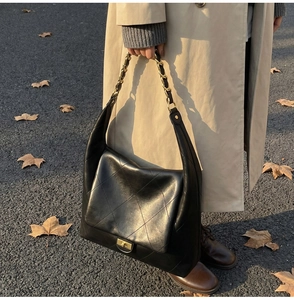 Detailed close-up of quilted black leather texture and gold chain strap on a shoulder bag