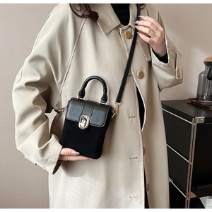 Detail of a black mini crossbody bag with mixed leather texture and gold twist-lock