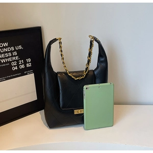 Black quilted leather shoulder bag with gold chain strap shown next to a 10-inch tablet