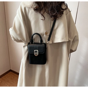 Model wearing minimalist black leather crossbody bag with elegant gold twist lock clasp