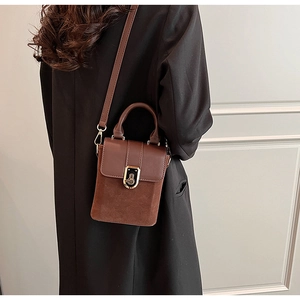 Brown crossbody box bag with gold buckle and mixed textures worn with a black suit