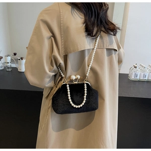 Détail d'un sac en peluche noire avec des poignées en perles et une chaîne bandoulière