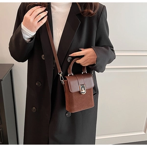Detailed view of a brown vintage box bag with leather splicing and metal twist lock closure