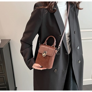 Detail of dark brown retro crossbody box bag with metal lock and chain on model