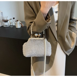 Sac à main gris en peluche avec fermoir perle et chaîne dans un café chic