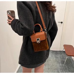 Brown two-tone shoulder bag with gold clasp shown on a model for size perspective