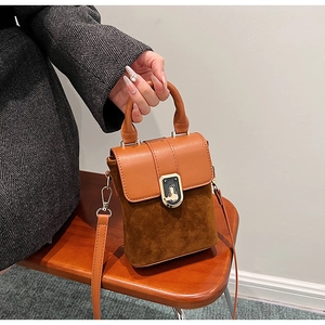 Close-up of brown textured leather crossbody bag with vintage gold metal clasp on a chair