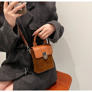 Detail of tan leather crossbody box bag shown on shoulder with tweed coat