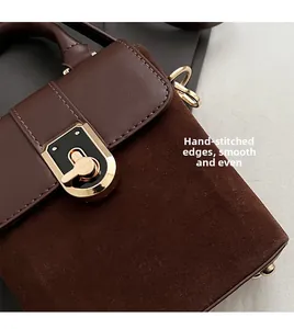 Detailed close-up of dark brown handbag showing stitching craft and gold metal lock