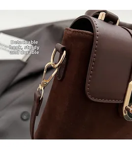 Detail of dark brown suede shoulder bag with gold metal hooks and neat stitching