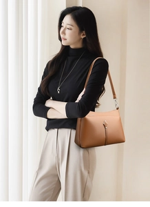 Close-up of brown litchi pattern leather texture and metal arrow buckle detail on handbag