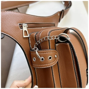 Detail of dark brown lychee leather texture and silver zipper on multi-pocket waist bag