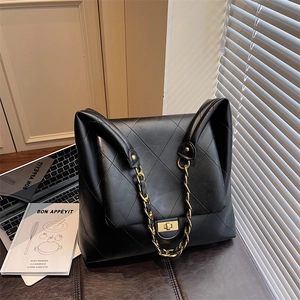 Quilted black shoulder bag with gold chain strap on a desk for office commuting