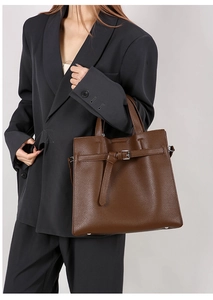 Detail view of the soft pebbled leather texture and silver buckles on a brown tote bag