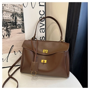 Detail of dark brown leather handbag with vintage gold metal twist lock and texture