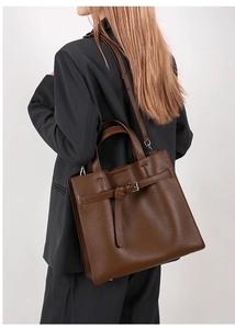 Detail of soft dark brown pebble leather texture and buckle strap on tote bag