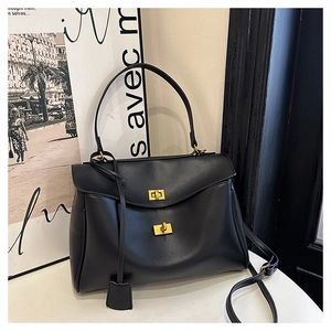 Detail view of black matte leather tote with golden twist locks and adjustable strap