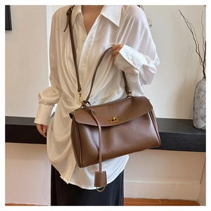 Detail of caramel brown leather bag with golden twist lock and adjustable shoulder strap