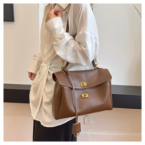 Detail of dark brown leather tote bag with double gold turn-lock closures and texture